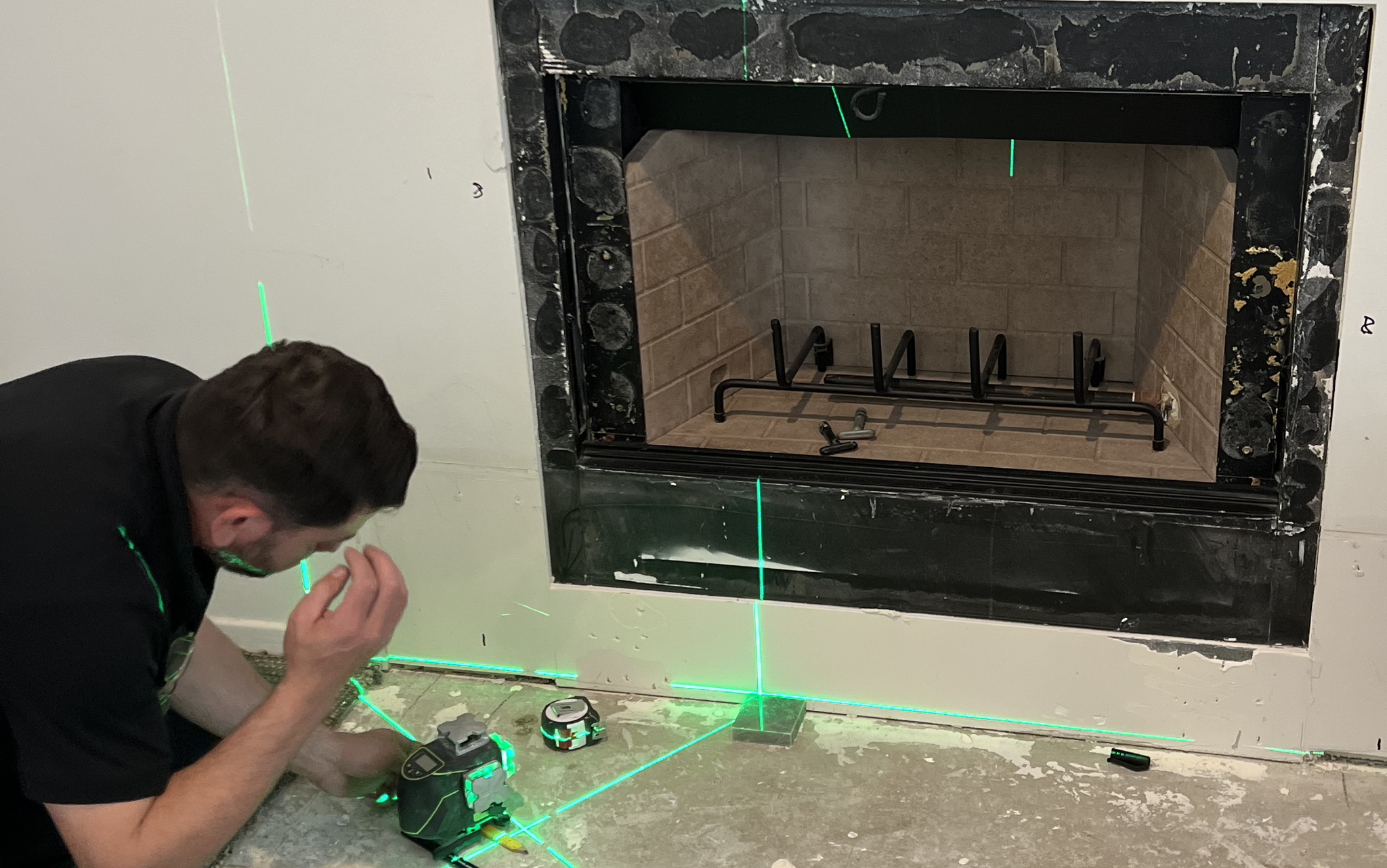 Fireplace installation in progress with laser alignment and site measurements